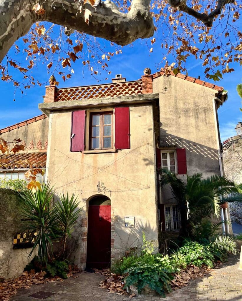 building with red shutters in Le Castellet